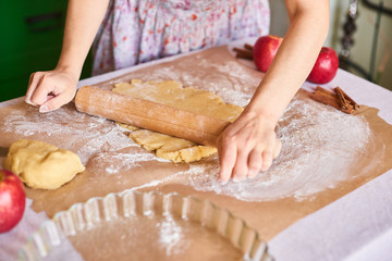 Woman kneading dough for the apple pie on kitchen table. Rustic style