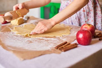 Woman kneading dough for the apple pie on kitchen table. Rustic style