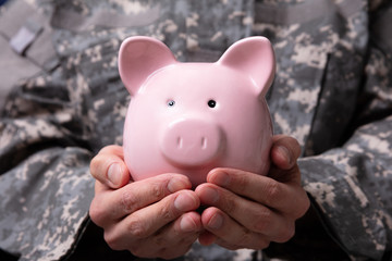 Soldier's Hand Holding Piggy Bank