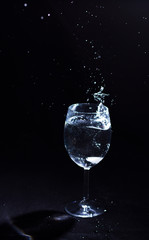 Transparent glass of water in the foreground on a black background