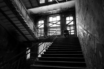 Fototapeta premium Silhouette of man sitting on stairs in ruined place.