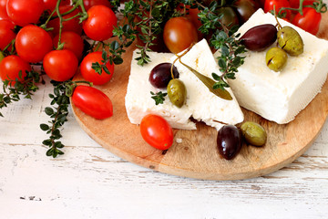 Fototapeta na wymiar Greek feta cheese, olives and cherry tomatoes on a wooden table