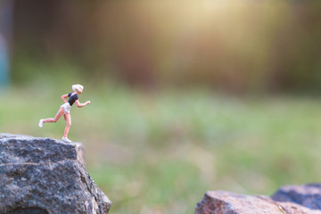 Miniature people : Running on rock cliff with nature background