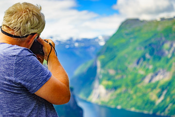 Tourist taking photo of fjord landscape, Norway