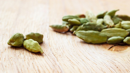Green cardamom pods on wooden background