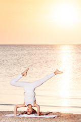 young girl doing yoga at sunrise on beach.