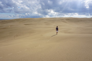 man walking alone in the desert lost in sand dunes lonely isolated and depressed dehydrated