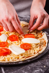 young woman in a gray aprong prepares a pizza margarita