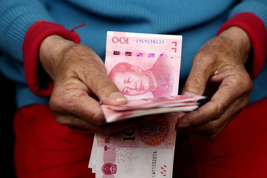 Elderly woman's hands counting Chinese Yuan banknotes, close up