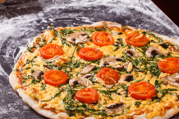 young woman in a gray aprong prepares a vegetarian pizza