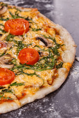 young woman in a gray aprong prepares a vegetarian pizza