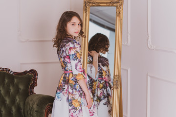 Little girl in romantic dress and fashionable kids look . Teen girl in interior 