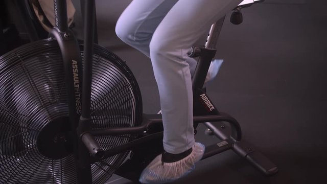 Closeup shoot of young attractive athlete healthy female with ponytail working out on the orbitrek being motivated and determined in the gym