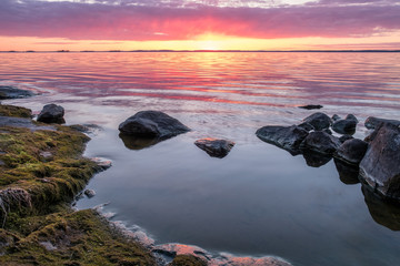 Scenic sunset with peaceful lake and rock at spring evening in Finland