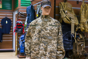 Camouflage clothes hanging on hangers in the room. a large number of military vehicles in the store