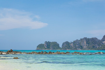 Blue sea and white sand with tropical mountains in the background