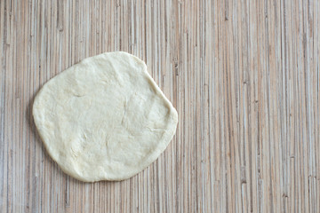 Yeast dough on the kitchen table is rolled out with a rolling pin for making a pie with a filling A cake of raw dough lies on the surface of the table for further preparation 