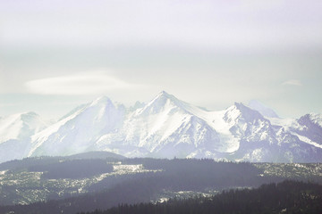 Fototapeta na wymiar Snowy mountaing peaks of Tatra wrapped in a slight fogg