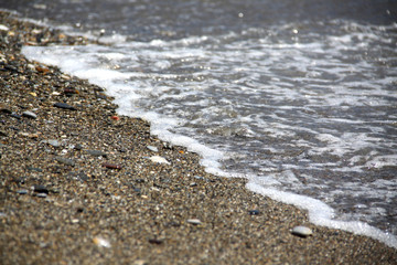 Sea tide. Shore with stone coating. Wave at sea. Background and texture.
