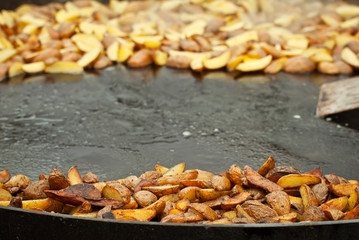 Roast potatoes in a large pan. Delicious food at the festival. Field kitchen at the hearth.