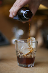 man holding a glass of coffee cold brew and ice on wooden table