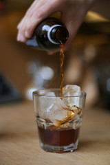 man holding a glass of coffee cold brew and ice on wooden table