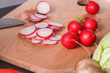 young woman in a gray apron cuts a radish