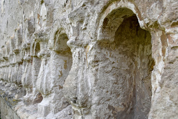 The ancient half-ruined synagogue. Stone relief columns carved in the wall. The texture of old dilapidated masonry. Stones covered with moss. Rashkov, Moldova. Selective focus.