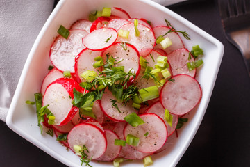 Radish salad in a white bowl on a dark background