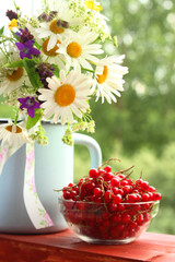 A bouquet of wildflowers and a glass bowl of red currant