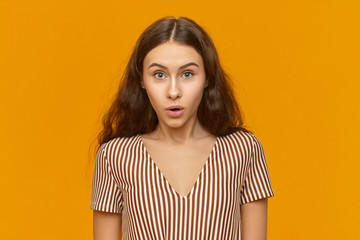 Are you kidding me? Pretty girl having amazed fascinated look, staring at camera in shock, astonished with unexpected twist in plot, watching TV series, posing at orange wall with mouth wide opened
