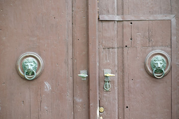 Old wooden front door. They are decorated with heads of lions.