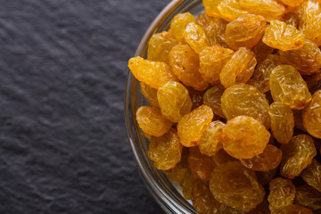 golden raisins on a dark stone background