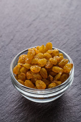 golden raisins on a dark stone background