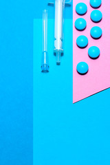 Medical stuff and pills minimalistic flat lay with copy space on a paper background of blue and pink.