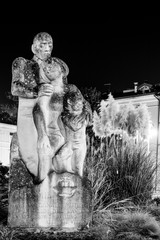 ancient monochrome figure of a hugging family on an italian square at night