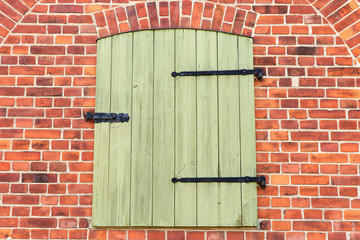Green locked wooden door in the red brick wall