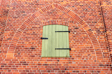 Obraz premium Green locked wooden door in the red brick wall