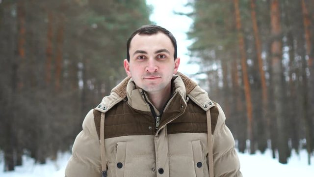 Portrait of smiling man in a jacket in the forest. Man stands in winter forest.