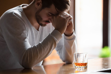 Man sitting on bar counter feels depressed drinking alcohol drink