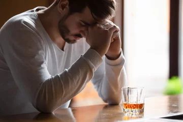 Gardinen Der Mann, der auf der Bartheke sitzt, fühlt sich deprimiert, wenn er Alkohol trinkt © fizkes