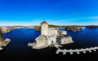 Beautiful aerial view of Olavinlinna, Olofsborg ancient fortress, the 15th-century medieval three - tower castle located in Savonlinna city on a sunny summer day, Finland. Shooting from a quadcopter.