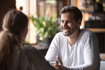 Rear view female sitting at speed dating with smiling man