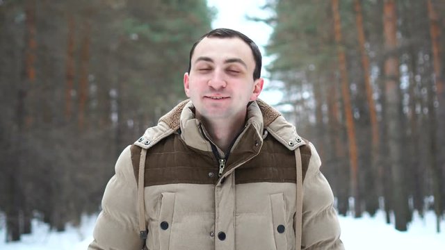 Portrait of a man in a jacket approving something by nodding his head. Man stands in winter forest.