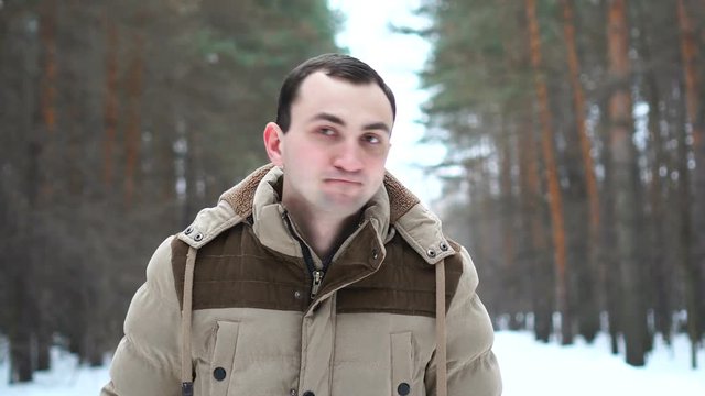 Portrait of man in jacket rejecting something by nodding his head. Man stands in winter forest