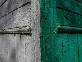 Corner of an old wooden fence of green and gray color. The boards laid in a row
