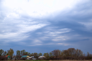 Rural landscape in dark colours with a dark ominous sky. Wavy low heavy clouds and sky