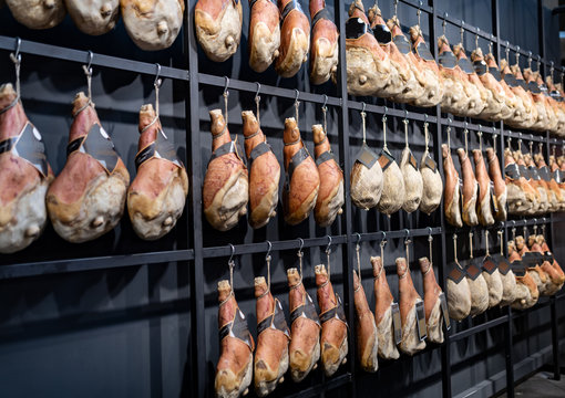 Prosciutti crudi, speck, ed affettati appesi alle rastrelliere pronti per la vendita al pubblico dei consumatori