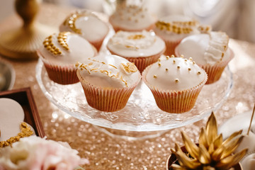 Delicious wedding cupcakes with glaze with gold details at the wedding buffet