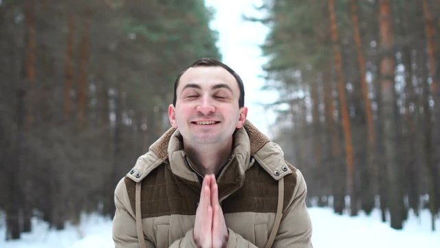 Portrait of amazed man in a jacket is showing wow emotion at camera. Man stands in winter forest